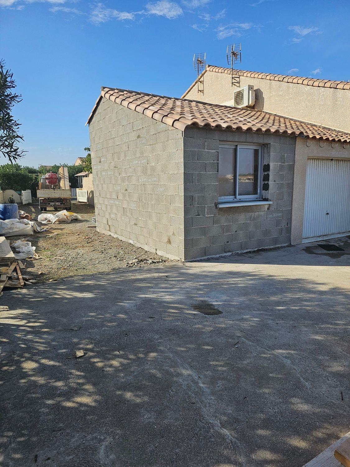 Extension en blocs béton accolée à une maison, toiture en tuiles posée, avant enduit